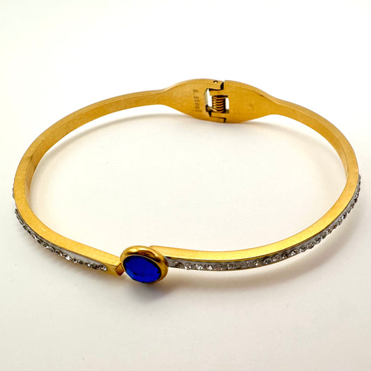 Goldfarbener Armreif mit saphirblauem Kristall und Strassbesatz