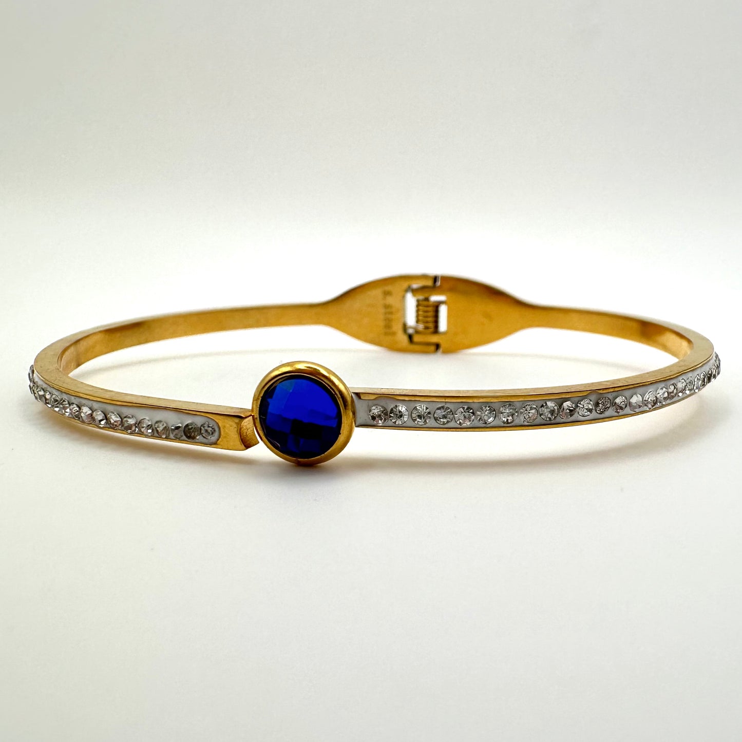Goldfarbener Armreif mit saphirblauem Kristall und Strassbesatz